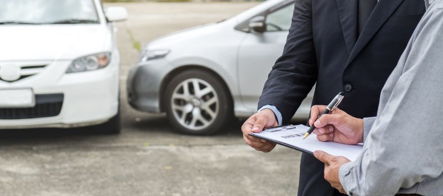 man signing paper in front of two cars