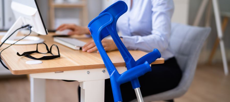woman sitting at a desk next to crutches